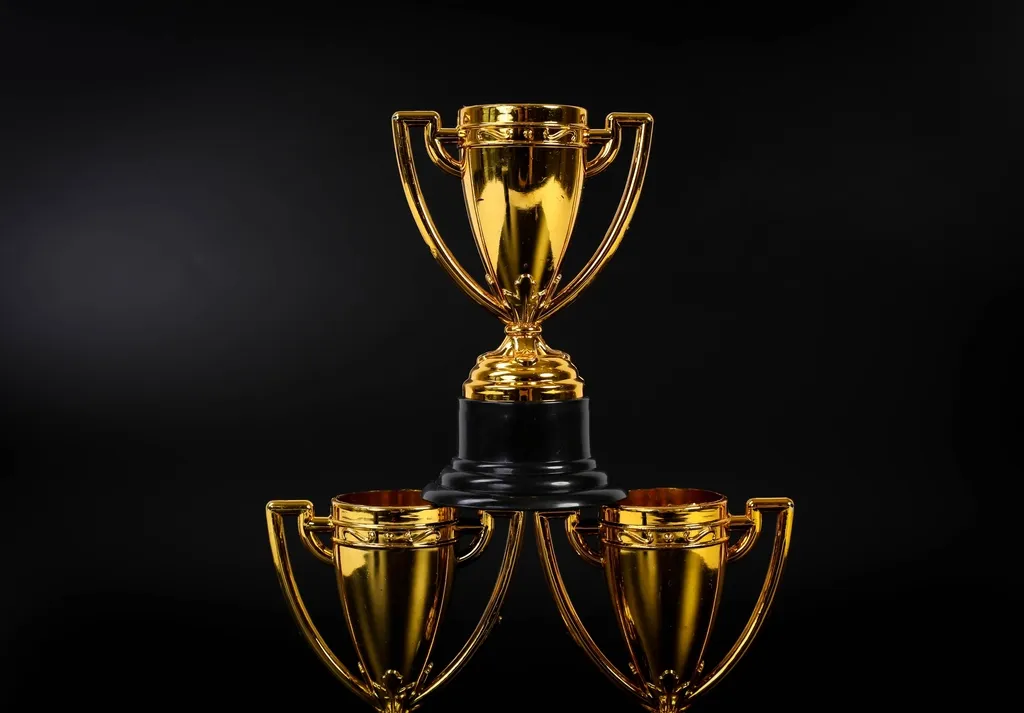 Três troféus dourados sobre fundo escuro
